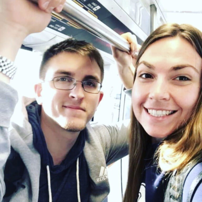 David and Teige smiling at camera holding onto the handles of a shuttle